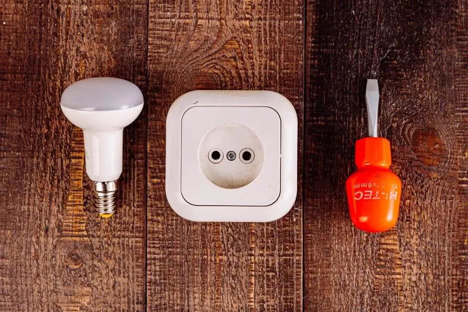 Flat lay of a lightbulb, socket, and screwdriver representing home appliance repair tools