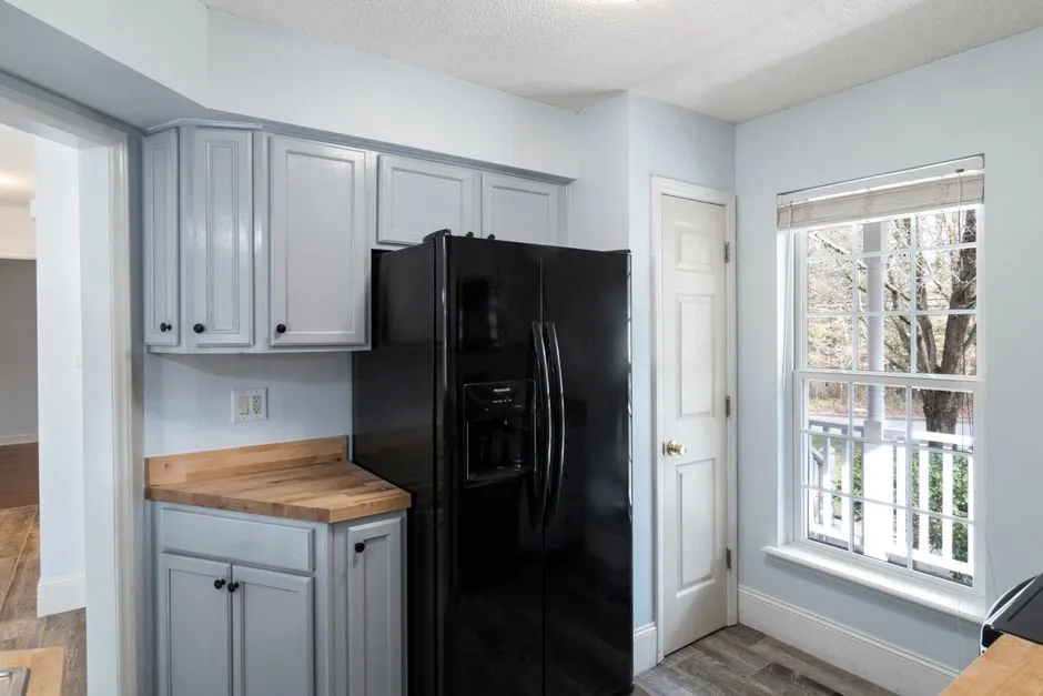 A modern kitchen refrigerator beside cabinetry and a window