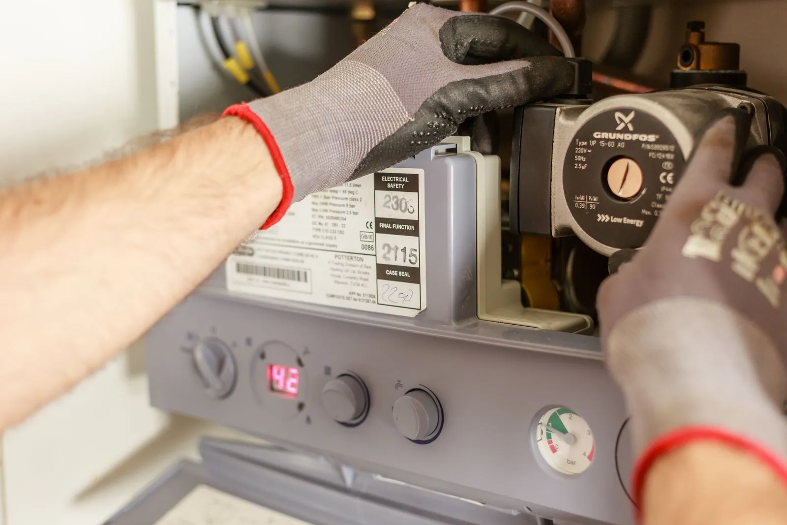 Close-up of hands adjusting controls on a home heating appliance